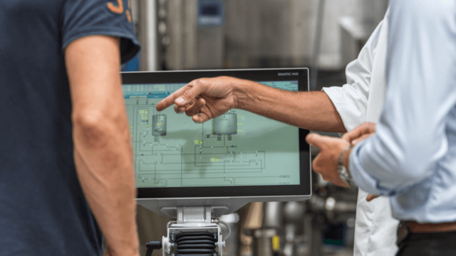 Group of workers following production line using monitor screen 640x360